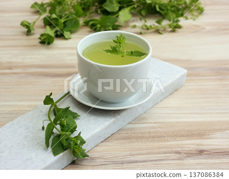 A cup of fresh tea from Chickweed, lat. Stellaria media on white marble. A cup of fresh tea from Chickweed, lat. Stellaria media on white marble. 137086384