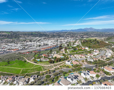 Aerial view over San Juan Capistrano, California, featuring the historic mission, library, sports courts, and an Amtrak train pulling into the downtown station. Aerial view over San Juan Capistrano, California, featuring the historic mission, library, sports courts, and an Amtrak train pulling into the downtown station. 137086403