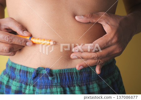 A person prepares to inject insulin in the abdomen area for diabetes management A person prepares to inject insulin in the abdomen area for diabetes management 137086877