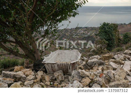 Stone ruins and ancient basin on hilltop with Black Sea coastline and New Athos town view in Abkhazia. Travel marketing, heritage tourism promotion and regional landscape Stone ruins and ancient basin on hilltop with Black Sea coastline and New Athos town view in Abkhazia. Travel marketing, heritage tourism promotion and regional landscape 137087312