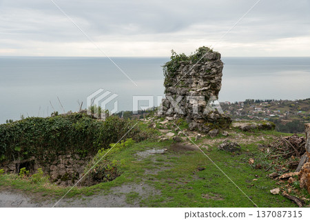 Anakopia fortress stone tower ruins overlooking Black Sea coastline and New Athos landscape under overcast sky in Abkhazia. Heritage tourism marketing, travel branding, history education Anakopia fortress stone tower ruins overlooking Black Sea coastline and New Athos landscape under overcast sky in Abkhazia. Heritage tourism marketing, travel branding, history education 137087315