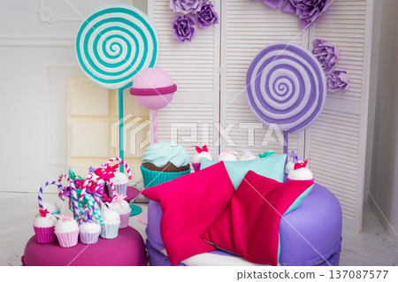 Colorful birthday background with cupcakes with candies and lollipops Colorful birthday background with cupcakes with candies and lollipops 137087577