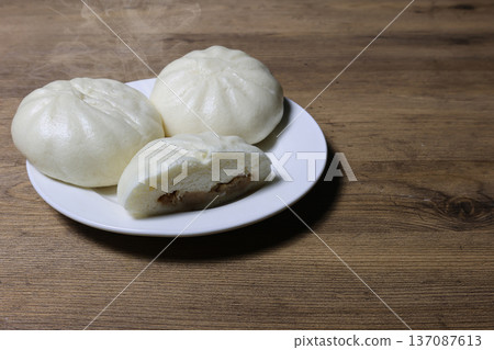 Steamed meat buns on a plate on a wooden background Steamed meat buns on a plate on a wooden background 137087613