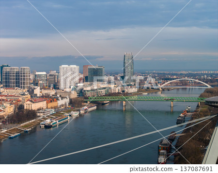 Aerial view of Bratislava, Slovakia, shows the Danube, green Stary most, white Apollo Bridge, Panorama City tower, River Park, Eurovea, and river boats in soft winter light. Aerial view of Bratislava, Slovakia, shows the Danube, green Stary most, white Apollo Bridge, Panorama City tower, River Park, Eurovea, and river boats in soft winter light. 137087691