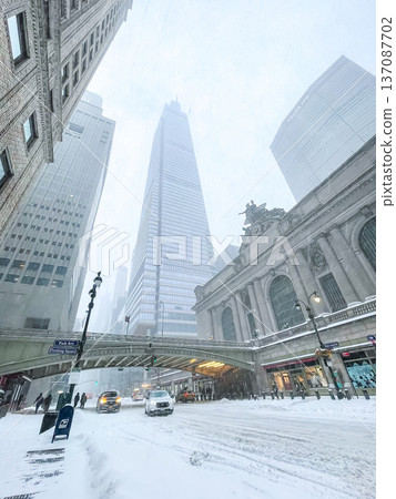Grand Central Terminal and One Vanderbilt rise over Park Avenue at Pershing Square as taxis and pedestrians move through slushy lanes under muted winter light and swirling snow. Grand Central Terminal and One Vanderbilt rise over Park Avenue at Pershing Square as taxis and pedestrians move through slushy lanes under muted winter light and swirling snow. 137087702