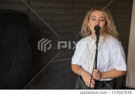 Caucasian woman singing into microphone in music studio.  137087836