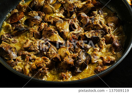 A bowl of meat with a creamy sauce. The meat is brown and has a crispy texture. The sauce is yellow and has a thick consistency. The bowl is placed on a countertop A bowl of meat with a creamy sauce. The meat is brown and has a crispy texture. The sauce is yellow and has a thick consistency. The bowl is placed on a countertop 137089119