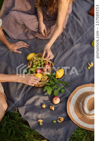 Playful couple exchanging fruit amidst scattered natural elements at sunset Playful couple exchanging fruit amidst scattered natural elements at sunset 137089353