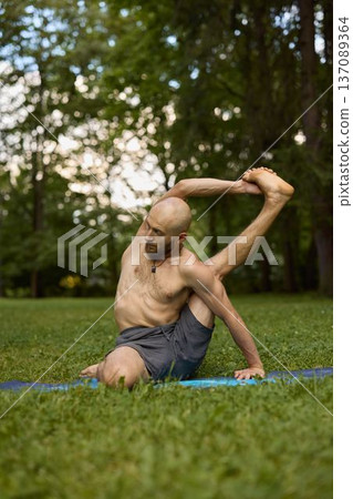 Tranquil man engages in focused spine mobility exercise outdoors Tranquil man engages in focused spine mobility exercise outdoors 137089364
