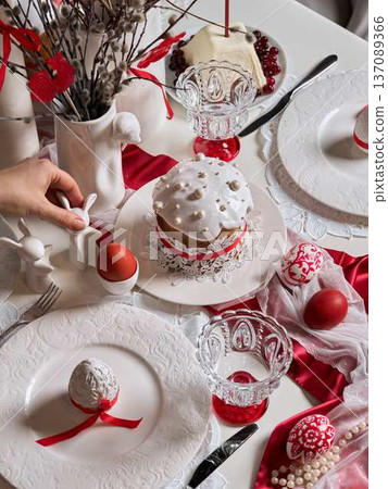 Two individuals organize crimson eggs among elegant dining setup 137089366
