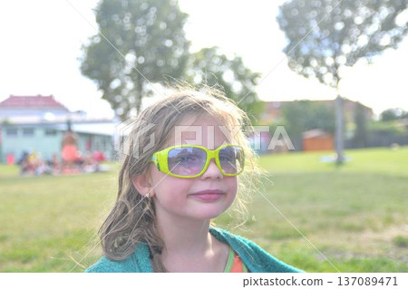 A sweet little girl wearing sunglasses at the pool. A smiling little girl wearing a beach towel at the pool. Happy kid at aqua. Little girl in sunglasses on a summer sunny day. Summer holiday concept A sweet little girl wearing sunglasses at the pool. A smiling little girl wearing a beach towel at the pool. Happy kid at aqua. Little girl in sunglasses on a summer sunny day. Summer holiday concept 137089471
