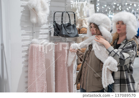 A mother and her teenage daughter shop for winter hats at a shopping mall. A mother and her teenage daughter shop for winter hats at a shopping mall. 137089570