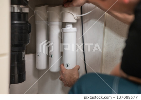 The technician changes water filters. The technician changes water filters. 137089577