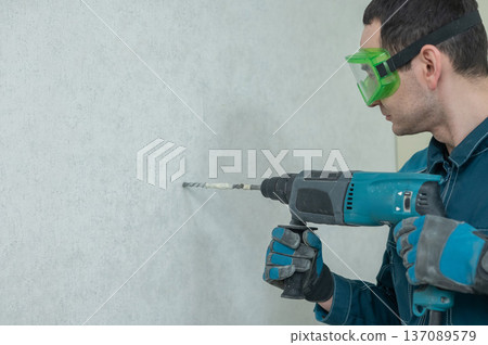 A man drills into a wall. A man drills into a wall. 137089579