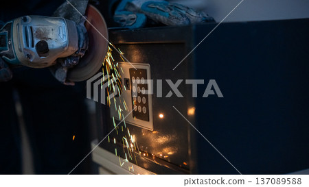 A man breaks into a safe with a grinder. A man breaks into a safe with a grinder. 137089588