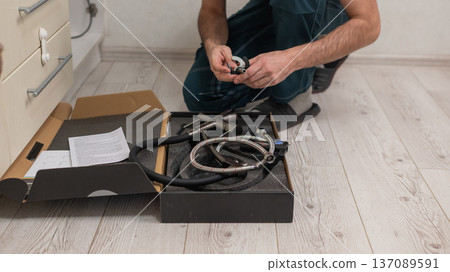 A plumber is replacing a faucet in the kitchen. A plumber is replacing a faucet in the kitchen. 137089591