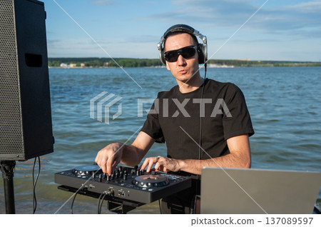 Caucasian man works as a DJ on the beach.  137089597