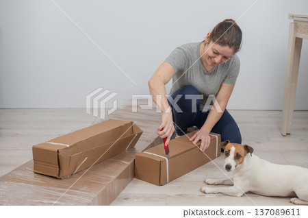 A Caucasian woman unpacks a box of furniture. A Caucasian woman unpacks a box of furniture. 137089611