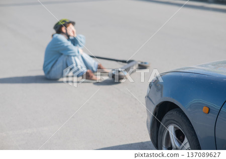 A Caucasian woman on a scooter after being hit by a car. 137089627