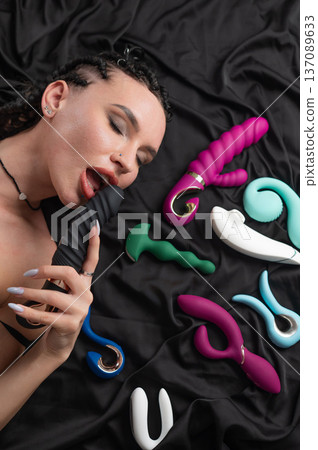 Portrait of Caucasian woman lying on bed among sex toys.  137089633