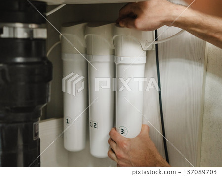 The technician changes water filters. The technician changes water filters. 137089703