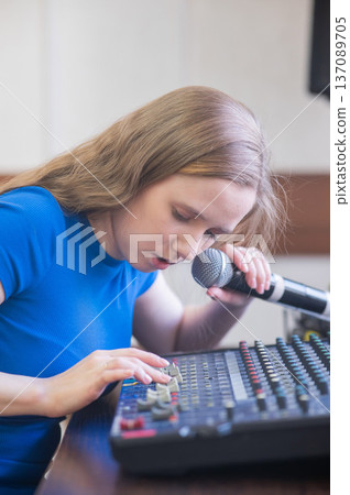 Young woman mixing live sound. Girl recording a song in the studio. Young woman mixing live sound. Girl recording a song in the studio. 137089705