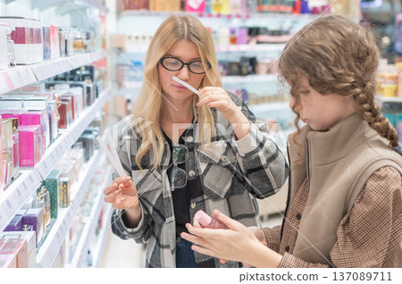 A mother and her teenage daughter are shopping for cosmetics. A mother and her teenage daughter are shopping for cosmetics. 137089711