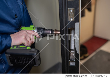 The technician installs a smart electronic lock on the front door. The technician installs a smart electronic lock on the front door. 137089757
