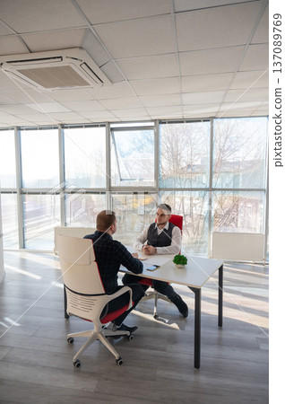 Two Caucasian men communicating at a business meeting.  137089769