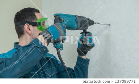 A man drills into a wall. A man drills into a wall. 137089771