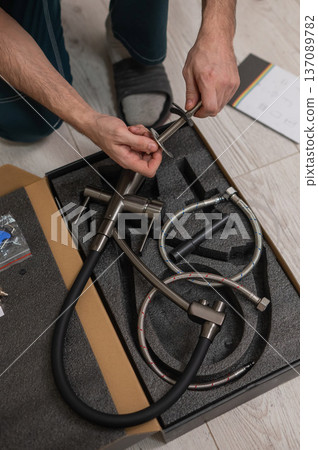 A plumber is replacing a faucet in the kitchen. A plumber is replacing a faucet in the kitchen. 137089782