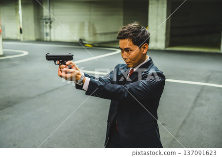 A man in a suit holds a gun 137091623