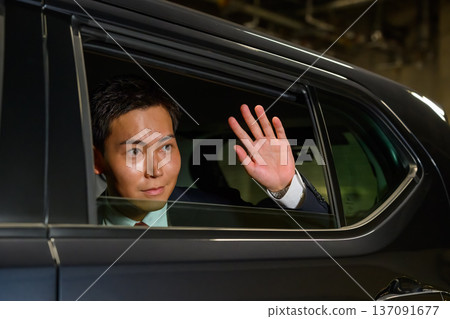 Man waving from inside a car 137091677