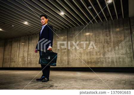一個穿西裝的男人拿著一個包包 137091683