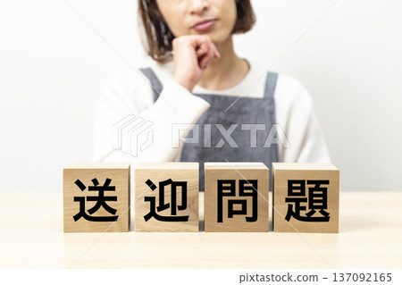 一位身穿圍裙的女士正在擔心一塊寫著「接送問題」的牌子。 一位身穿圍裙的女士正在擔心一塊寫著「接送問題」的牌子。 137092165