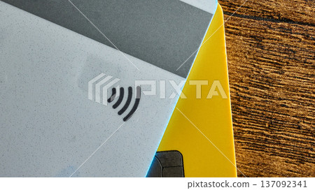 Close-up of credit cards showing the contactless payment symbol on a wooden background Close-up of credit cards showing the contactless payment symbol on a wooden background 137092341