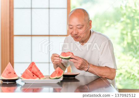 Middle-aged men, seniors, elderly men eating watermelon at the dining table Middle-aged men, seniors, elderly men eating watermelon at the dining table 137092512