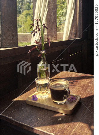 Coffee and water arranged neatly on wooden tray, placed near a bright window, creating a warm, cozy setting. A glass of water, coffee, and a decorative plant sitting on the table Coffee and water arranged neatly on wooden tray, placed near a bright window, creating a warm, cozy setting. A glass of water, coffee, and a decorative plant sitting on the table 137096029