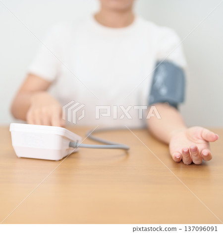 woman checking Blood pressure by Blood pressure monitor with Cuff. Systolic, SYS, Diastolic, DIA, Pulse, Hypertension, Hypotension, Heart rate, Cardiovascular Disease and May World hypertension day 137096091