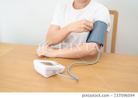 woman checking Blood pressure by Blood pressure monitor with Cuff. Systolic, SYS, Diastolic, DIA, Pulse, Hypertension, Hypotension, Heart rate, Cardiovascular Disease and May World hypertension day 137096094