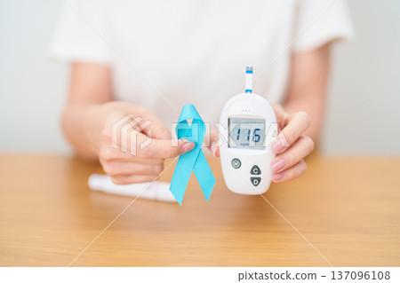 Hand show Blue Ribbon and digital blood glucose meter with lancet pen. high blood sugar level, November World Diabetes Day, Awareness month, Glycemia,, Hyperglycemia and insulin testing and checking Hand show Blue Ribbon and digital blood glucose meter with lancet pen. high blood sugar level, November World Diabetes Day, Awareness month, Glycemia,, Hyperglycemia and insulin testing and checking 137096108