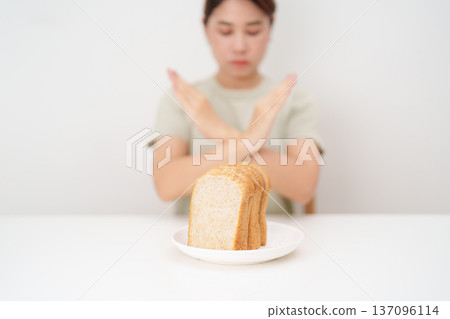 Unhappy woman showing Rejecting gesture and refusing to eat bread. concept of gluten intolerance, gluten sensitivity, carb loading concerns, or a disliking for unhealthy dietary habits Unhappy woman showing Rejecting gesture and refusing to eat bread. concept of gluten intolerance, gluten sensitivity, carb loading concerns, or a disliking for unhealthy dietary habits 137096114