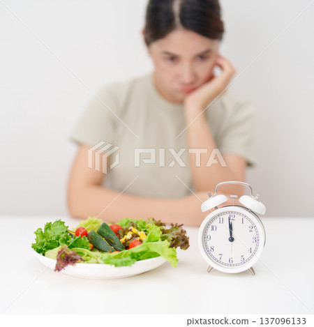 hungry woman with fresh organic vegetables plate and clock. intermittent fasting, IF, time to eating, nutrition control, weight loss, clean eating, Healthy food eating, Wellness, dieting and lifestyle hungry woman with fresh organic vegetables plate and clock. intermittent fasting, IF, time to eating, nutrition control, weight loss, clean eating, Healthy food eating, Wellness, dieting and lifestyle 137096133