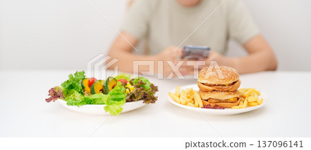 happy woman with Healthy and Unhealthy Food Choice. Comparison of Calories and Nutrition of vegetables Salad plate and Hamburger. diet planning, weight loss management, junk food and habit lifestyle happy woman with Healthy and Unhealthy Food Choice. Comparison of Calories and Nutrition of vegetables Salad plate and Hamburger. diet planning, weight loss management, junk food and habit lifestyle 137096141