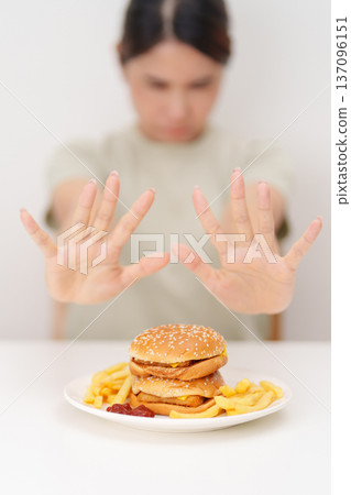 Unhappy woman showing Rejecting and refusing with Juicy beef burger, potato chips and carbonated Soft drinks. Unhealthy, High calorie, Fast food craving, Obesity, diet, weight loss and junk food 137096151