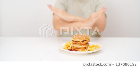 Unhappy woman showing Rejecting and refusing with Juicy beef burger, potato chips and carbonated Soft drinks. Unhealthy, High calorie, Fast food craving, Obesity, diet, weight loss and junk food Unhappy woman showing Rejecting and refusing with Juicy beef burger, potato chips and carbonated Soft drinks. Unhealthy, High calorie, Fast food craving, Obesity, diet, weight loss and junk food 137096152