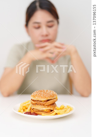Unhappy woman disgust gesture and Bored to eat Juicy beef burger and potato chips. Unhealthy, High calorie, Fast food craving, Obesity, diet, weight loss and junk food Unhappy woman disgust gesture and Bored to eat Juicy beef burger and potato chips. Unhealthy, High calorie, Fast food craving, Obesity, diet, weight loss and junk food 137096155