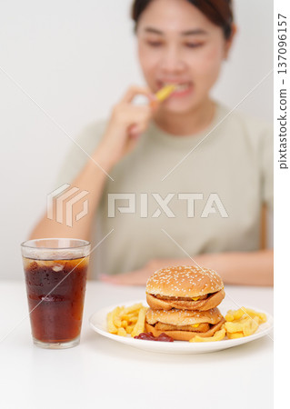 woman eating Juicy beef burger with melted cheddar cheese, potato chips and carbonated Soft drinks. Unhealthy, High calorie, Fast food craving, Obesity, diet, weight loss, junk food and lifestyle woman eating Juicy beef burger with melted cheddar cheese, potato chips and carbonated Soft drinks. Unhealthy, High calorie, Fast food craving, Obesity, diet, weight loss, junk food and lifestyle 137096157