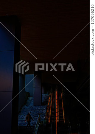 A pedestrian wearing a helmet walking between buildings A pedestrian wearing a helmet walking between buildings 137096216