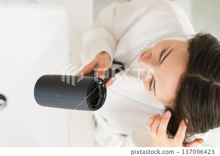 A woman drying her hair with a hair dryer Beauty image 137096423